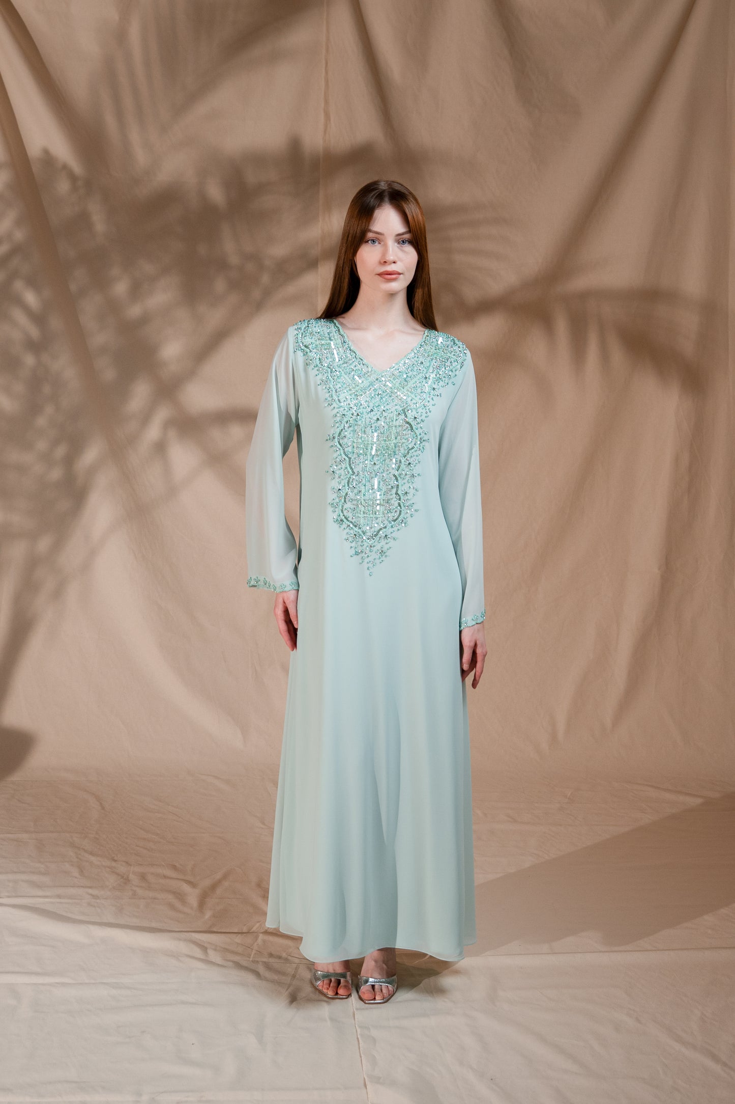 Woman wearing a light blue dress with lace details against a brown fabric background