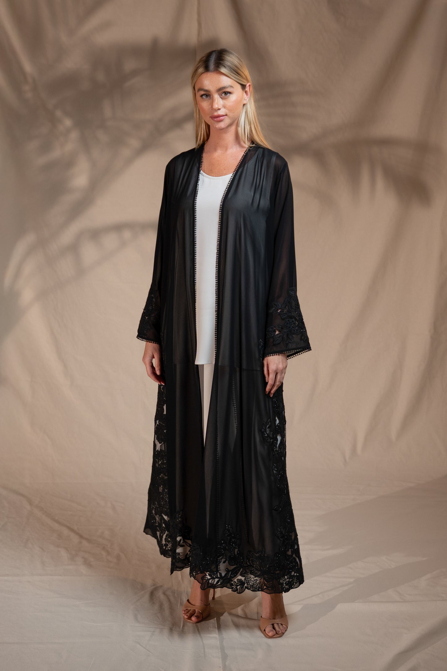 Woman wearing a black lace robe over a white top against a beige background