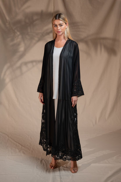 Woman wearing a black lace robe over a white top against a beige background
