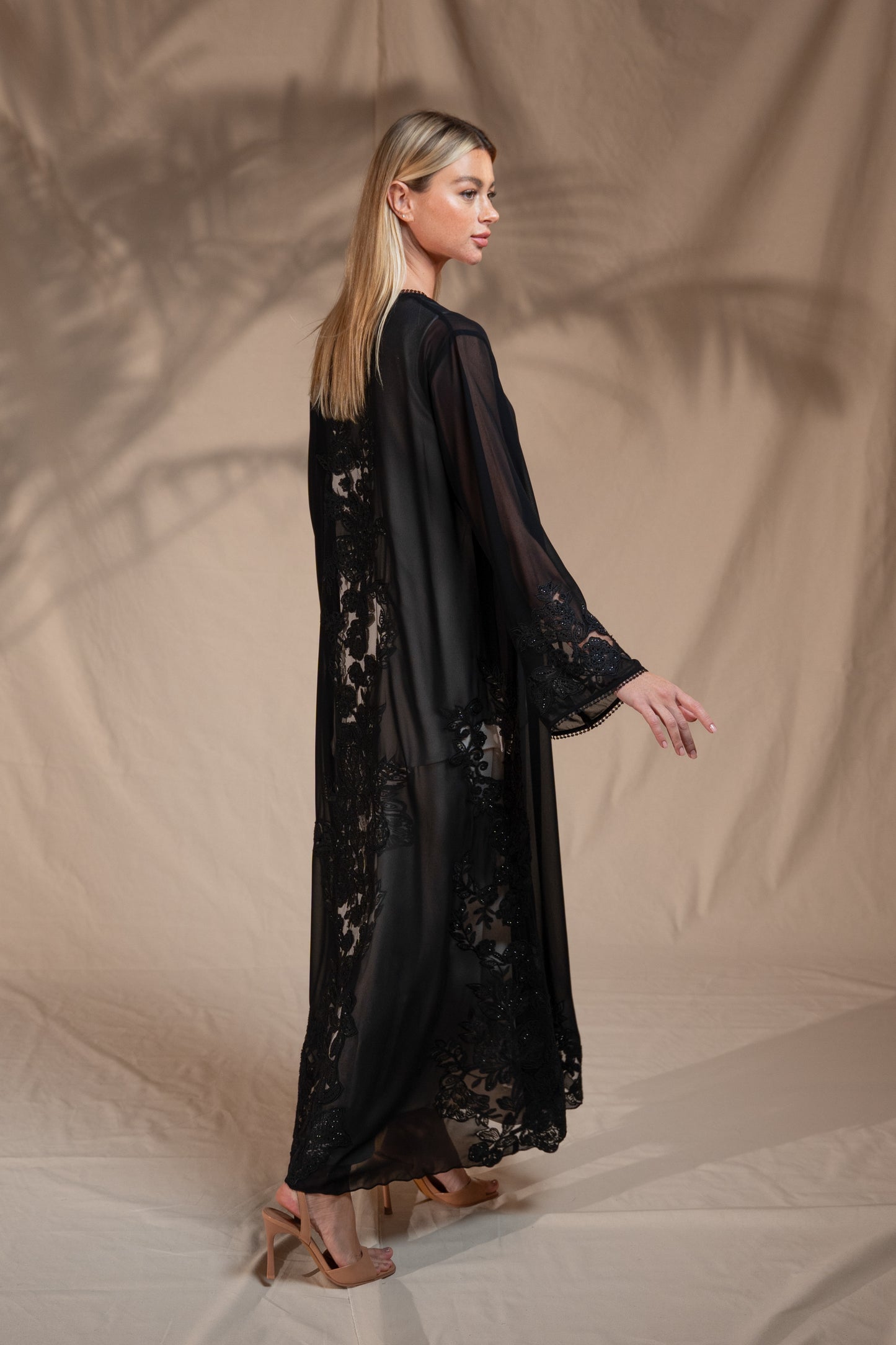 Woman wearing a black lace dress against a beige background