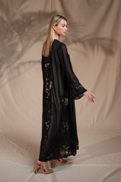 Woman wearing a black lace dress against a beige background