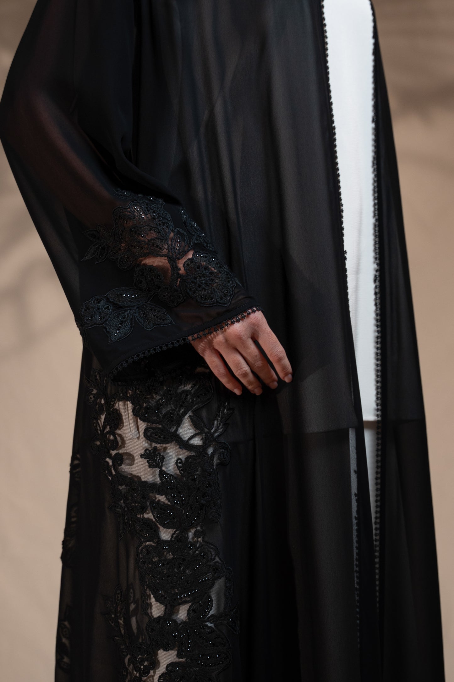 Black lace abaya with sheer sleeves on a neutral background